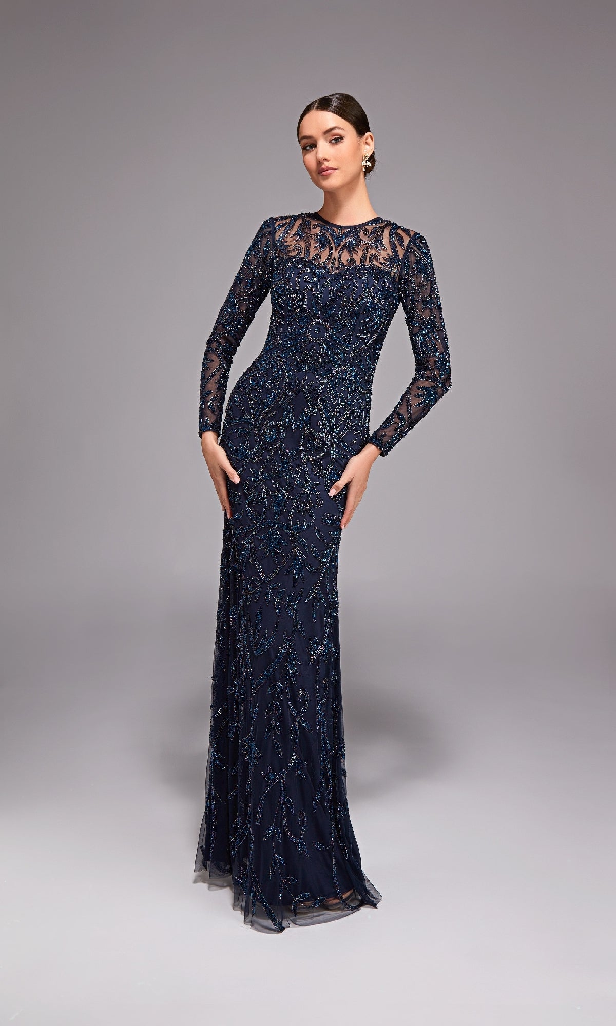 Wearing the Alyce 27778, a long navy blue beaded evening gown with sheer sleeves, this elegant look is a perfect choice for a mother of the bride against a simple gray background.